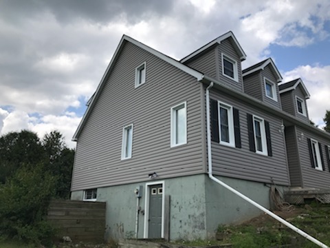 Taupe vinyl siding with white eavestroughs and downspouts on a three-storey home