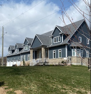 Navy blue siding with dormers, stone accents and white trim on a large custom home