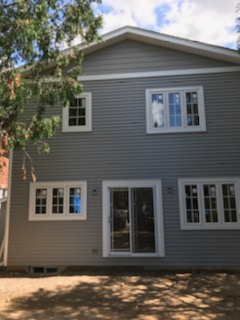 Grey horizontal vinyl siding with white window trim on a two-storey rear elevation